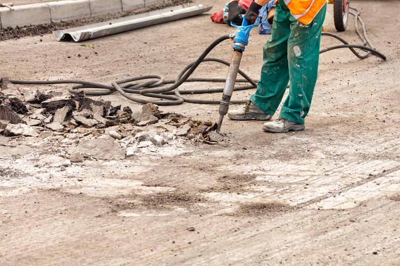 Worker operating a jackhammer for concrete demolition