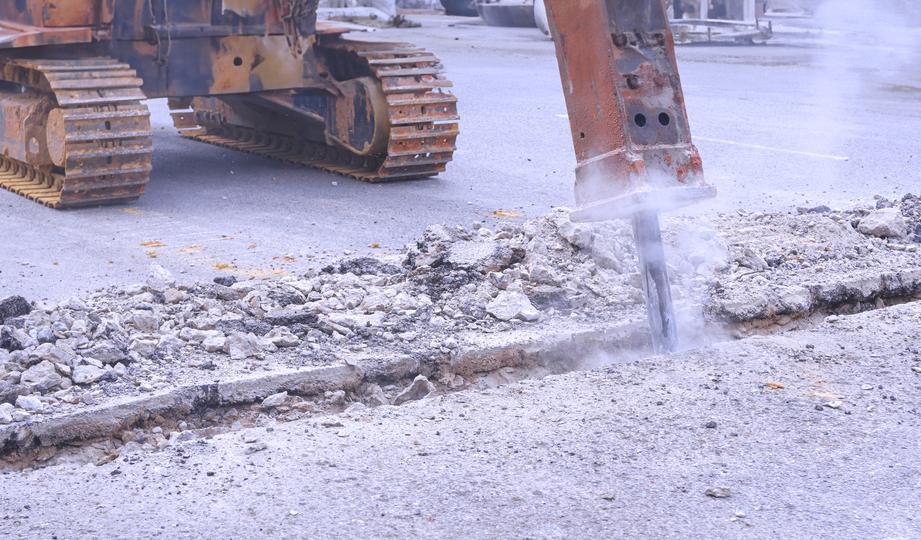 Worker operating a jackhammer for concrete demolition